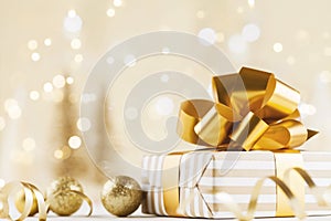 Christmas gift box against golden bokeh background. Holiday greeting card.