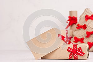 Christmas gift box with blank greeting label and red bow and ribbon closeup on white wood board with copy space.