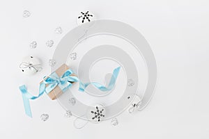 Christmas gift box with blue ribbon and jingle bell on white background from above. Holiday greeting card. Mockup. Flat lay.