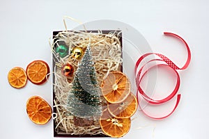 Christmas gift box with christmas decorations, balls, dried orange slices and red ribbon on white background.