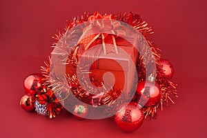Christmas gift box with decorations and color ball on red background