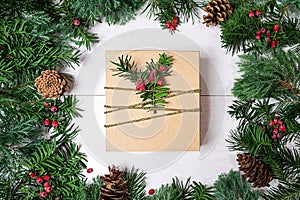 Christmas gift box and fir tree branches with red berries on wooden background.