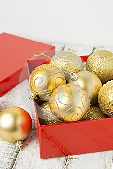 Christmas Gift Box with golden baubles and Decorations. White rustic wooden table