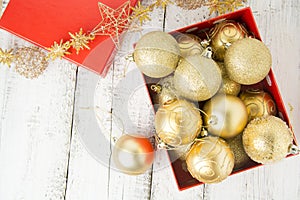 Christmas Gift Box with golden baubles and Decorations. White rustic wooden table