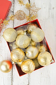 Christmas Gift Box with golden baubles and Decorations. White rustic wooden table