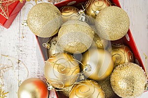 Christmas Gift Box with golden baubles and Decorations. White rustic wooden table