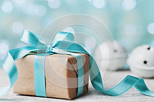 Christmas gift box and jingle bell against blue bokeh background. Holiday greeting card.