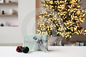 Christmas gift box over Christmas tree and winter holiday decorations at background