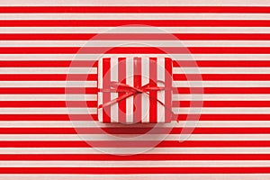 Christmas gift box on pink and red striped wrapping paper.