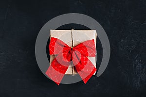 Christmas gift box. Christmas present box with red ribbon bow on dark stone background