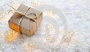 Christmas gift box with raffia ribbon and lights in the snow photo