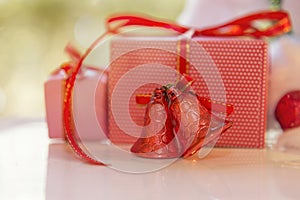 Christmas gift box, red jingle bell and blurred fir tree against