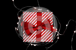 Christmas gift box with red ribbon encircled with illuminated ga