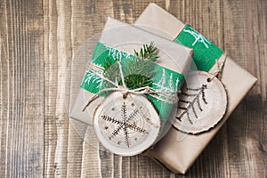 Christmas gift box in rustic style wrapped in paper with decor of wooden sliced with woodburning symbol.