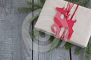 Christmas gift box on rustic table, decor reindeer, handicraft wrapping, parchment, fir tree twigs. Top view.