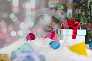 Christmas gift box on snow floor and decorated Christmas tree with blurred abstract bokeh glitter background