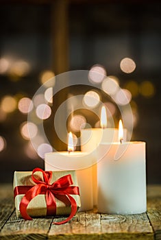 Christmas gift box with three white candles and lights background