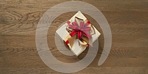 Christmas gift box tied with red and golden bow over a wooden table