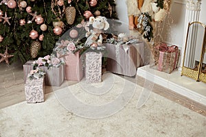 Christmas gift box under Chrismas tree lies on white carpet near fireplace
