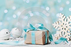 Christmas gift box and white jingle bell against blue bokeh background. Holiday greeting card.