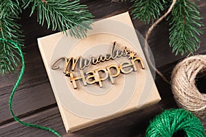 Christmas gift box with wooden lettering miracles happen. Gifts wrapping ideas. Natural design.