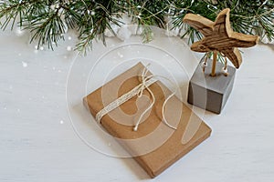 Christmas gift box wrapped in brown craft paper and tied knot. Decorative star on the shiny festive table. Zero waste christmas,
