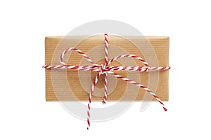 Christmas gift box wrapped in craft paper with striped baker`s twine bow isolated on white background