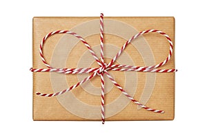 Christmas gift box wrapped in craft paper with striped twine bow isolated on white background