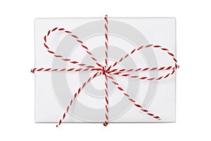 Christmas gift box wrapped in white paper with striped string bow isolated on white background