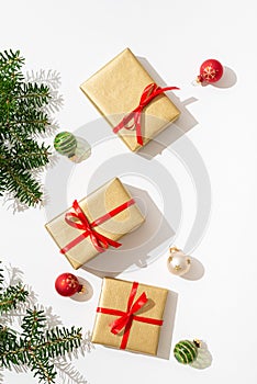 Christmas gift boxes background. New year Presents in golden wrapping paper with red ribbons, balls and fir branches on white