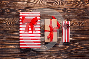 Christmas gift boxes collection in craft paper with red ribbons on rustic dark wooden background. Preparation for holidays. Top