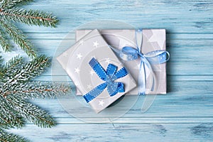 Christmas gift boxes and fir branch with snow, wooden background, top view