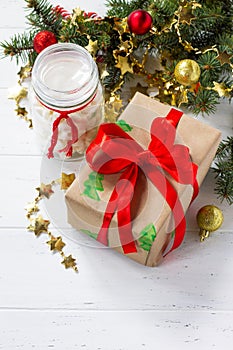 Christmas gift boxes and a jar of marshmallows with a Christmas tree on a white wooden table.