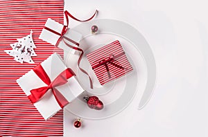 Christmas gift boxes with red ribbon, decoration, pine cones on white and red paper background.