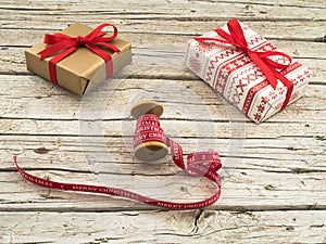 Christmas gift boxes and red ribbon on wooden background