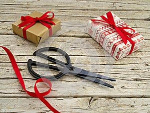 Christmas gift boxes, scissor and ribbon on wooden backgroun