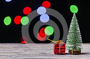 Christmas gift boxes under pine tree on wooden table over bokeh background