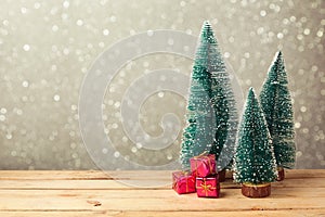 Christmas gift boxes under pine tree on wooden table over bokeh background