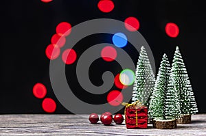 Christmas gift boxes under pine tree on wooden table over bokeh background