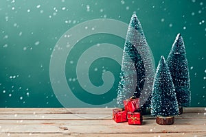 Christmas gift boxes under pine tree on wooden table over green background