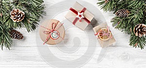 Christmas gift boxes on white wooden background with Fir branches, pine cones.