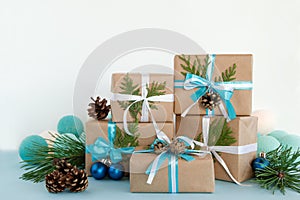 Christmas gift boxes wrapped of craft paper, blue and white ribbons and Christmas lights on the blue and white background.