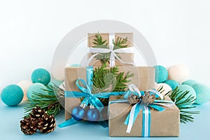 Christmas gift boxes wrapped of craft paper, blue and white ribbons and Christmas lights on the blue and white background.