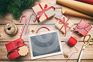 Christmas gift boxes wrapping and a blank blackboard on wooden background, copy space, top view