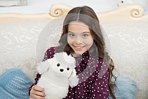 Christmas gift concept. Child cute small girl playful hold white dog plush toy. Kid little girl play toy dog puppy sofa