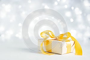 Christmas gift with a gold bow on a sparkling bokeh background. Copy space for text