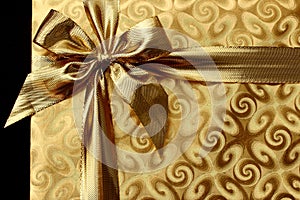 Christmas gift in gold paper with bow. background
