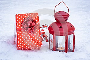Christmas gift and lantern with a burning candle in the snow, Christmas card
