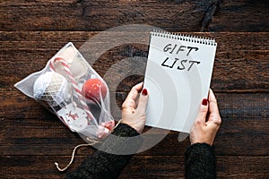 Christmas gift list, keeping track gifts christmas season. Female hands with open notepad and text Gift List on wooden