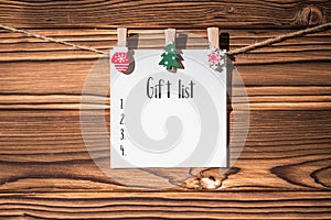 Christmas gift list on the paper sticker hanging on a rope on wooden clothespins. concept. Christmas and winter decoration.